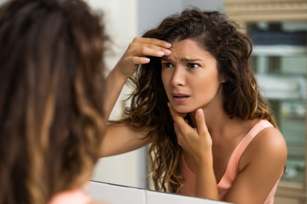 Woman looking at her face in the mirror